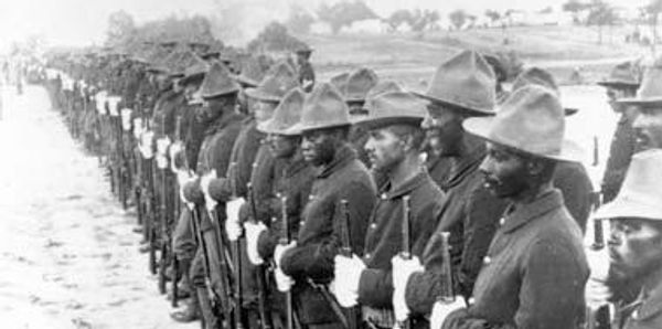 Historical photo of African soldiers in uniform standing in formation.