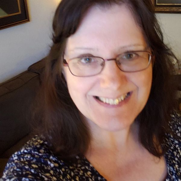 Smiling woman with glasses indoors.