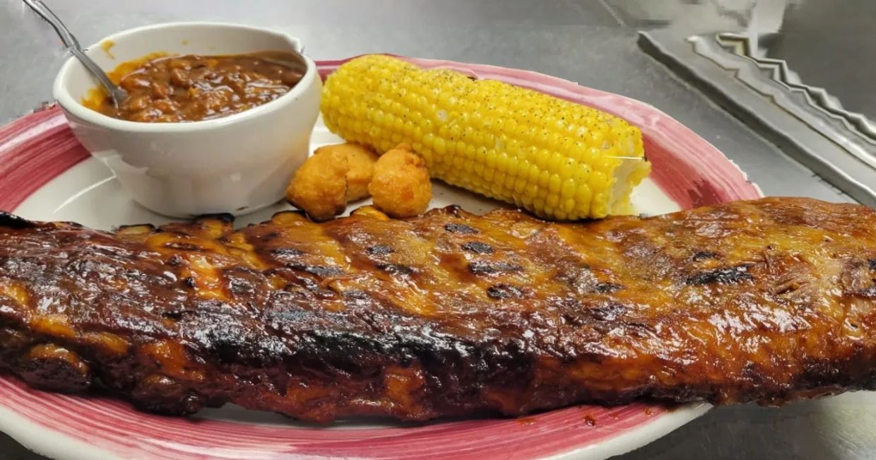 a plate of grilled steak and corn with sauce