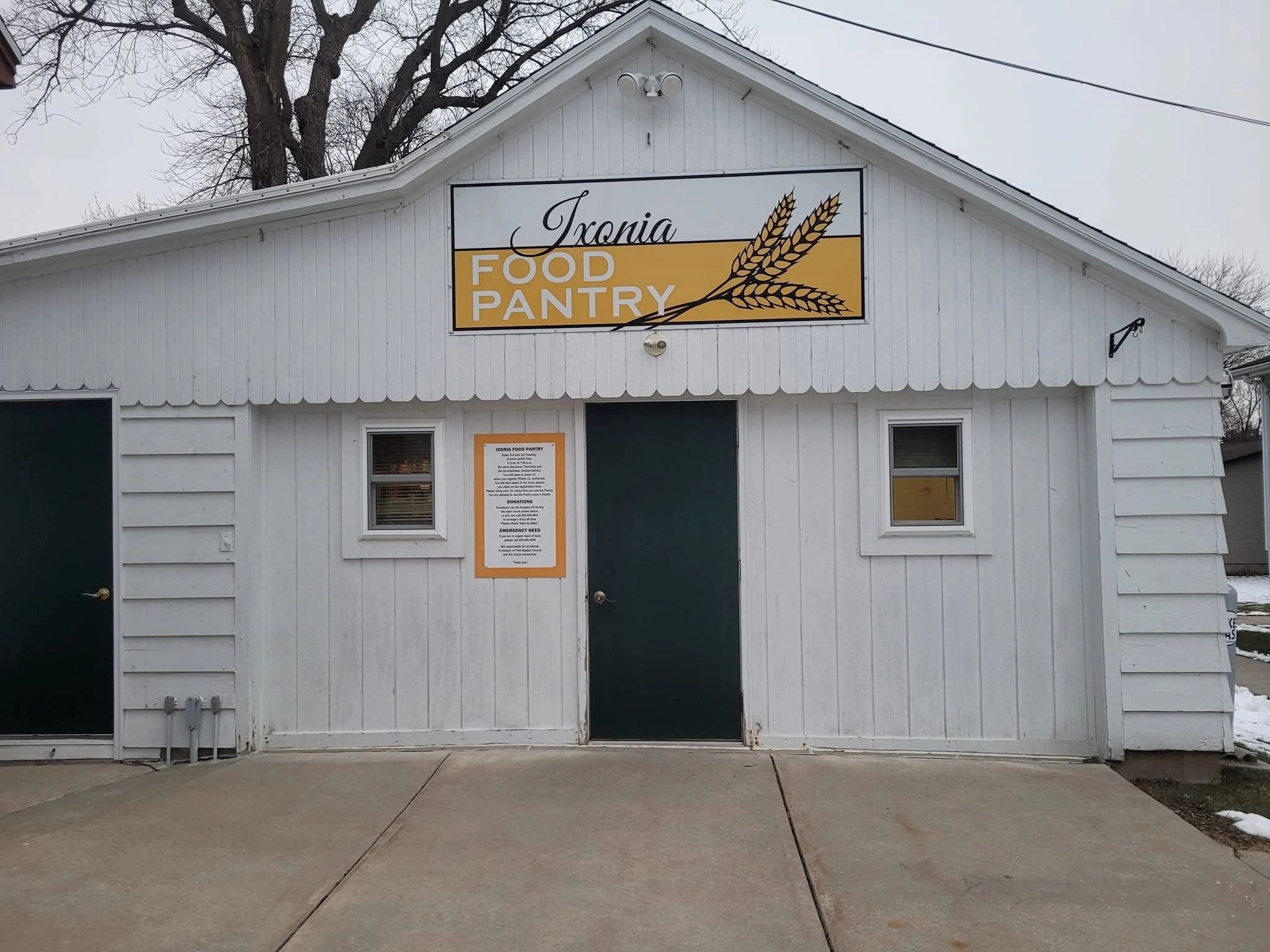 Exterior view of the white Ixonia Food Pantry building with signage and two doors.