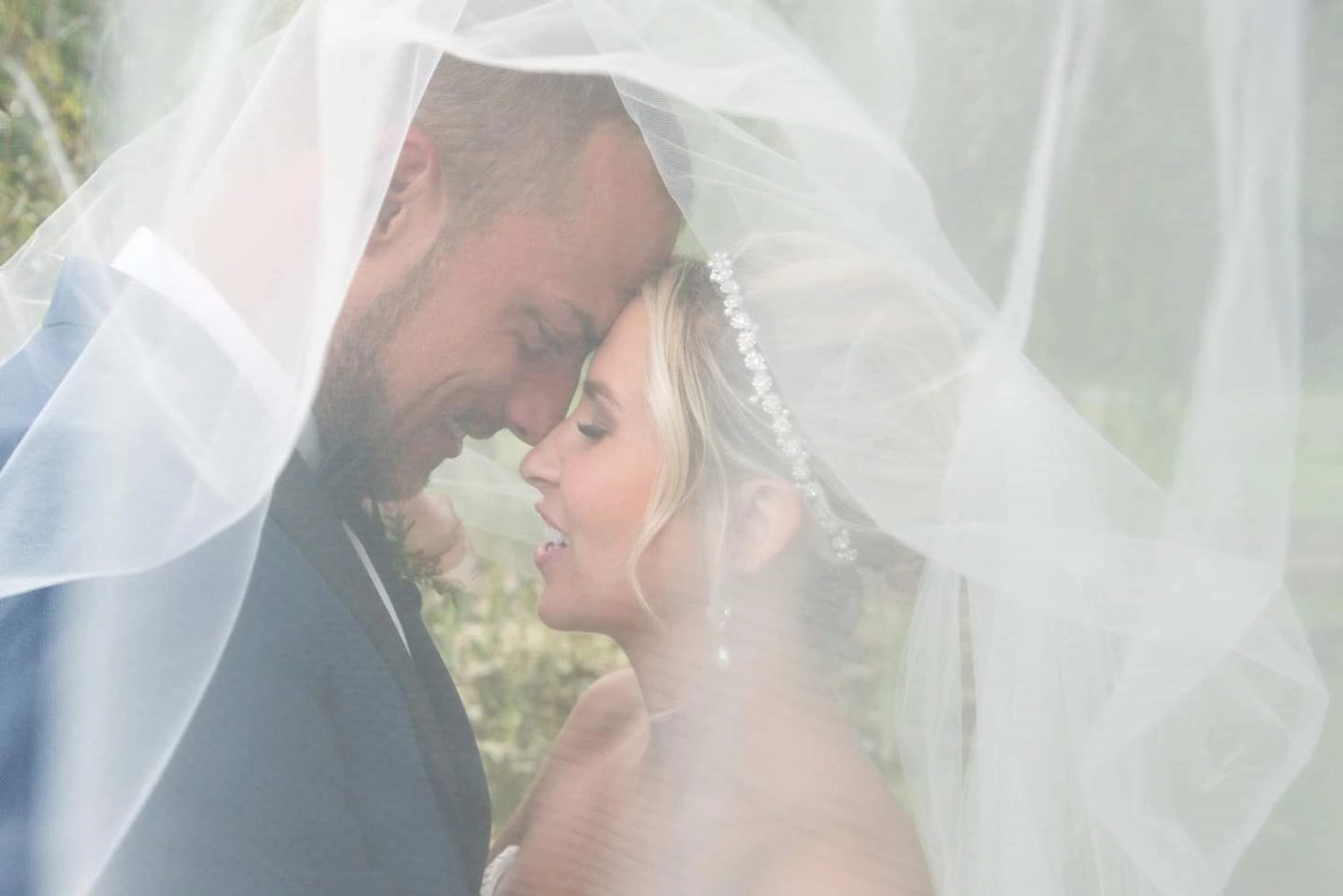 Bride and groom share a tender moment under the wedding veil.