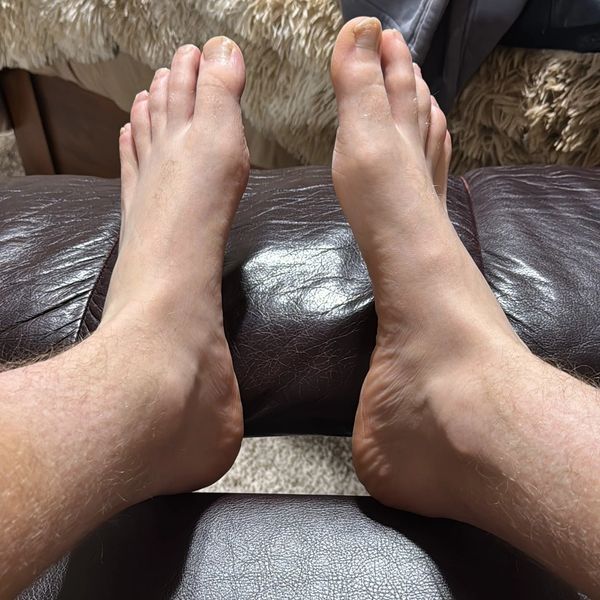 A pair of bare feet resting on a leather surface.