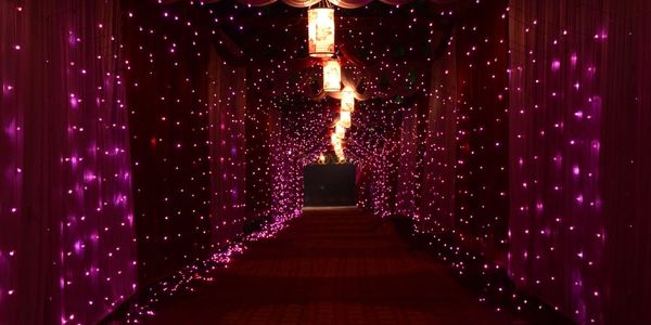 A hallway adorned with purple fairy lights and hanging lanterns creating a magical atmosphere.