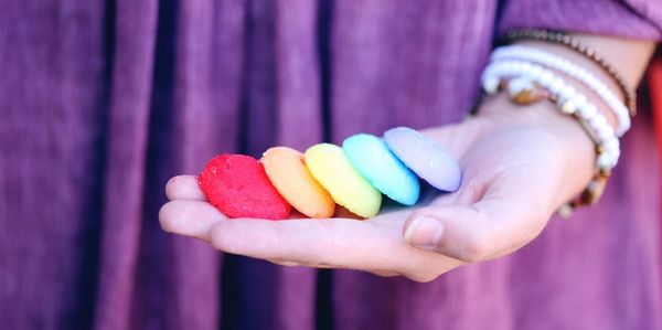 Hand holding colorful rainbow macaron cookies in a row.