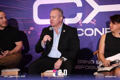 Three panelists discuss at a tech conference, holding microphones.