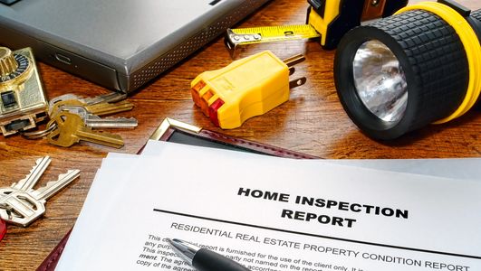 Home Inspection Report on table with flashlight and outlet tester