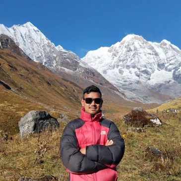 Man in sunglasses and red jacket in mountainous area.