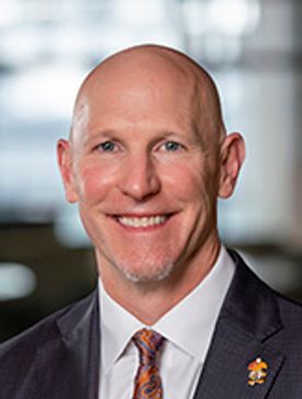 Smiling bald man in suit jacket and tie.