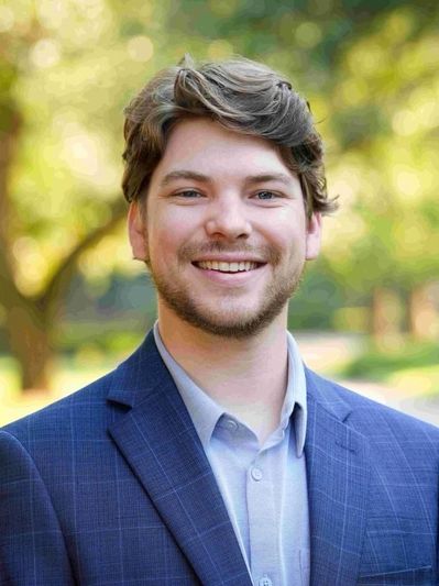 Smiling man in a blue suit outdoors.
