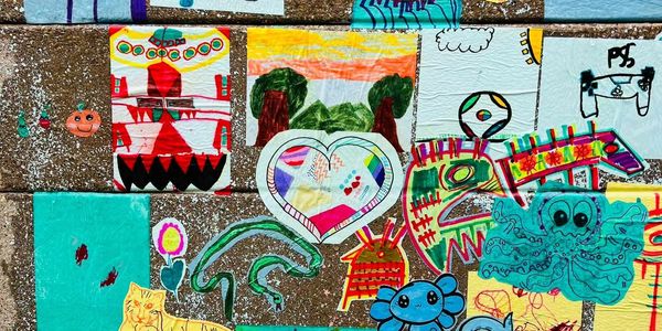 Colorful children's artwork displayed outdoors on a stone surface.