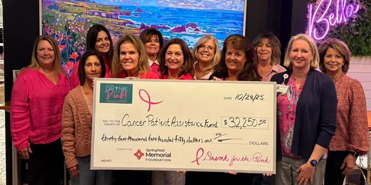 Group of women presenting a large check for cancer patient assistance.