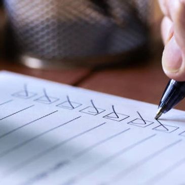 Hand checking off boxes on a checklist with a pen.