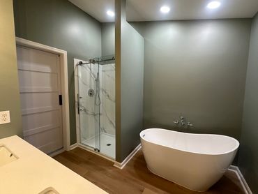 Modern bathroom with freestanding tub and glass shower enclosure.