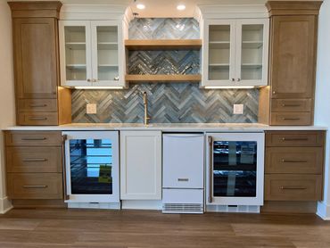 Modern kitchen with wood and white cabinetry, blue herringbone tile backsplash, and built-in appliances.