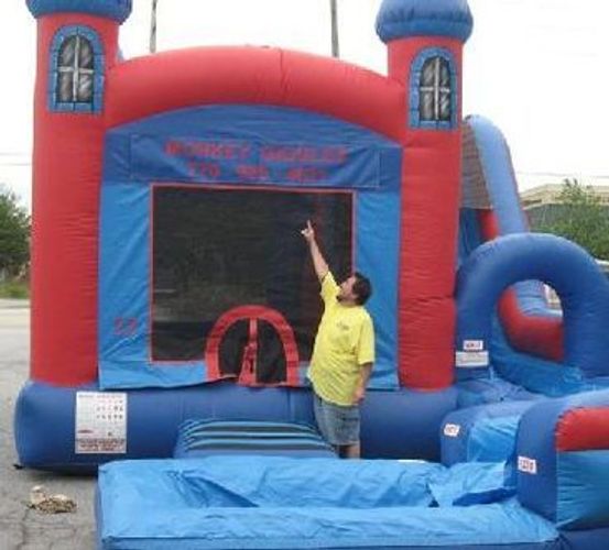 Red and blue inflatable bounce house with slide from Monkey Giggles rentals.