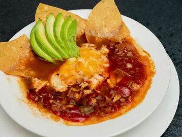Plate of Mexican food with avocado slices and tortilla chips.