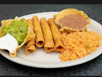 Mexican plate with taquitos, rice, guacamole, sour cream, and beans.
