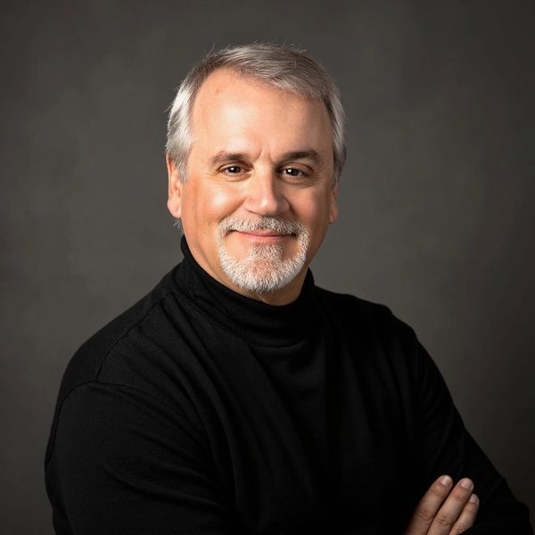 Smiling middle-aged man with gray hair and beard.
