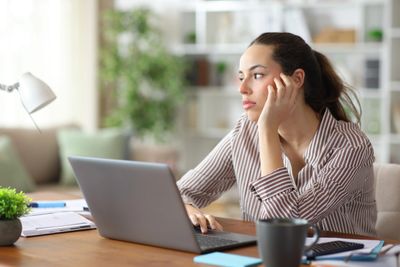 Person working on a laptop at home, appearing tired and mentally drained from burnout and work stres