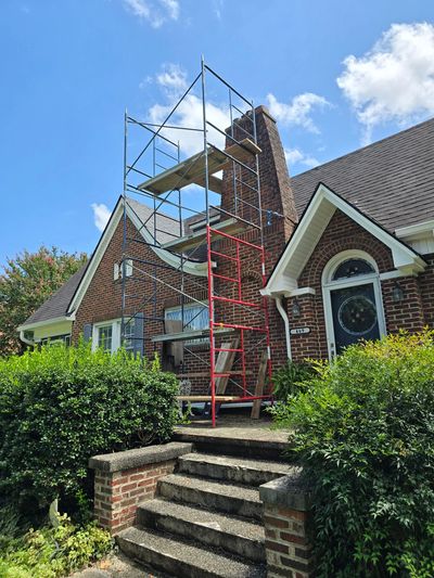 Scaffolding set up by a brick chimney on a house.