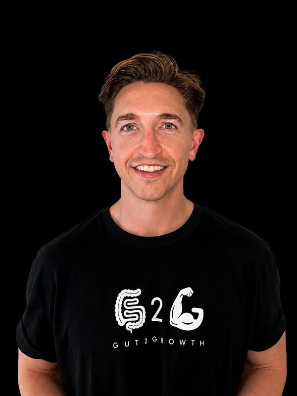 Smiling man wearing a black "GUT2GROWTH" t-shirt.