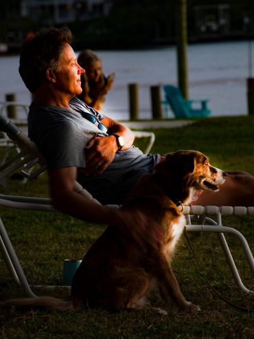 Man and his dog both watching the sunset as that warm glow provides me with ideal lighting.