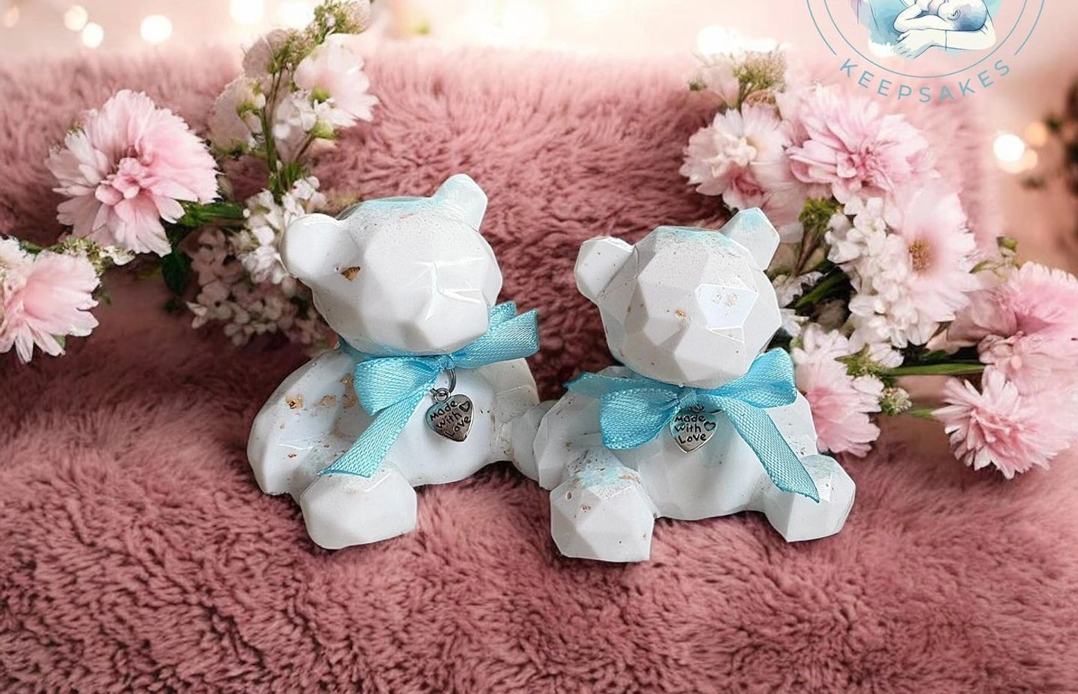 Two white geometric teddy bears with blue bows on a pink fuzzy background.