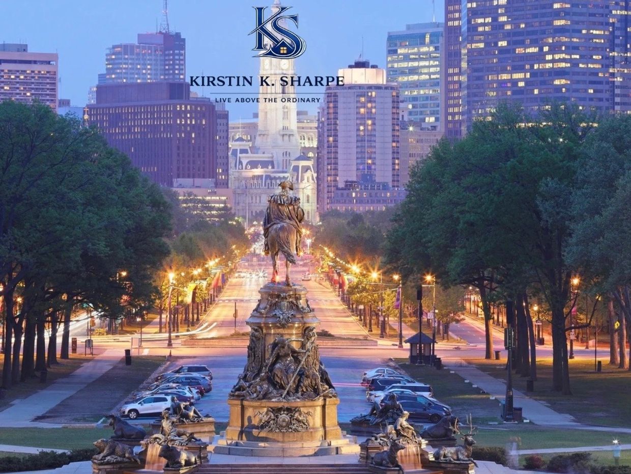 Cityscape with statue and illuminated street at dusk.