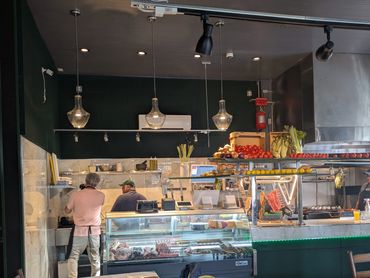 Cozy restaurant kitchen with chefs preparing food and fresh produce on display.