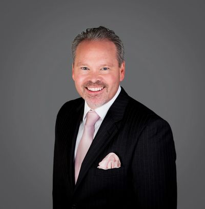 Smiling man in a suit with a light pink tie.
