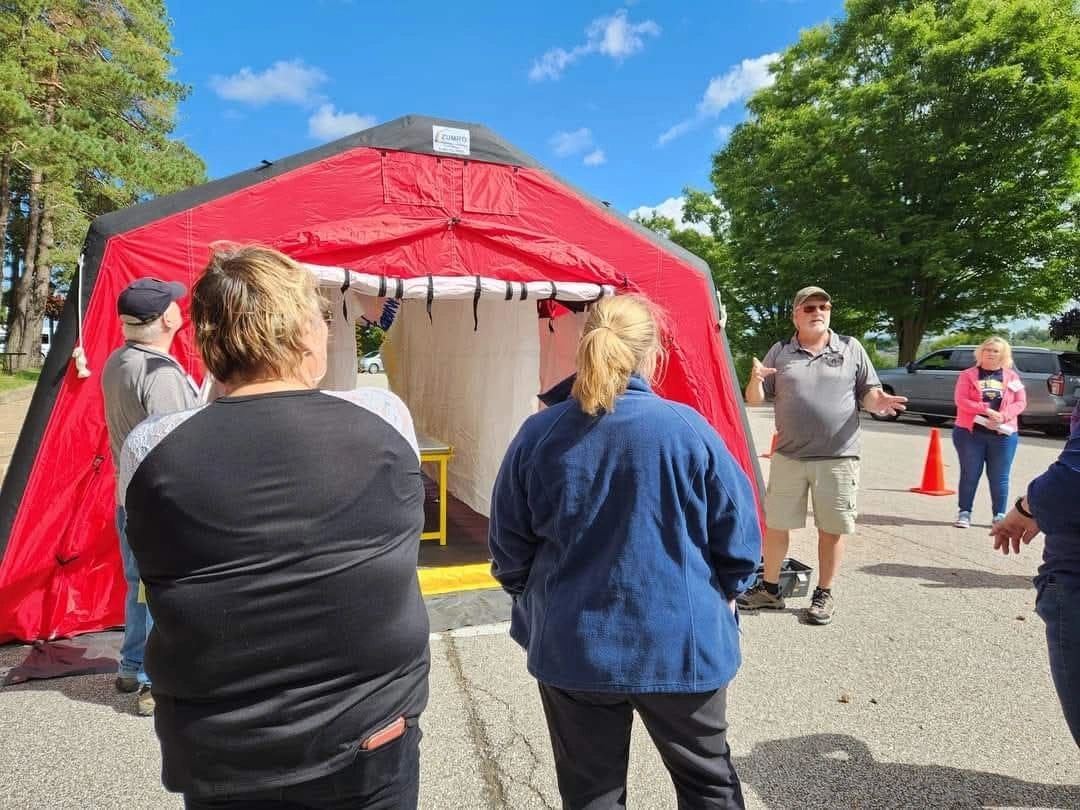 People gathered near a red tent outdoors.