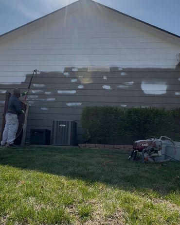 A picture of me in the middle of spray painting a home.