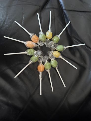 Colorful lollipops arranged in a circular pattern on black leather.