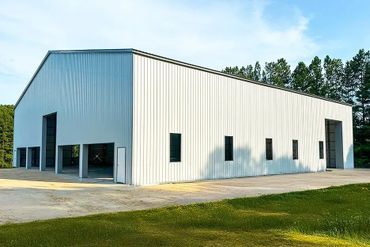 Large white metal warehouse building with multiple entrances and windows.