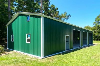 Large green metal building with multiple garage doors and a side door.