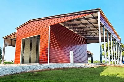 A large red metal barn with an open side and white support beams.