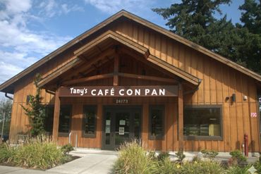 Exterior view of Tany's Café Con Pan in a wooden building with greenery and blue sky.