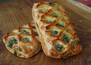 Golden puff pastries with spinach and cheese filling on a wooden surface.