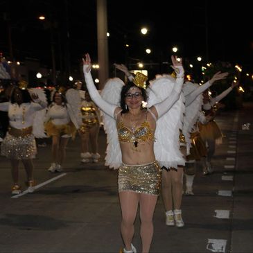 Performers in gold and white costumes dancing in a nighttime parade.
