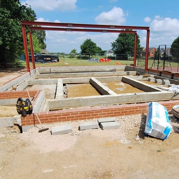 Construction site with foundation and steel frame under blue sky.