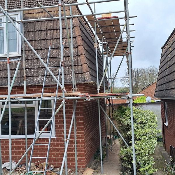 Scaffolding set up around a brick house for roofing work.