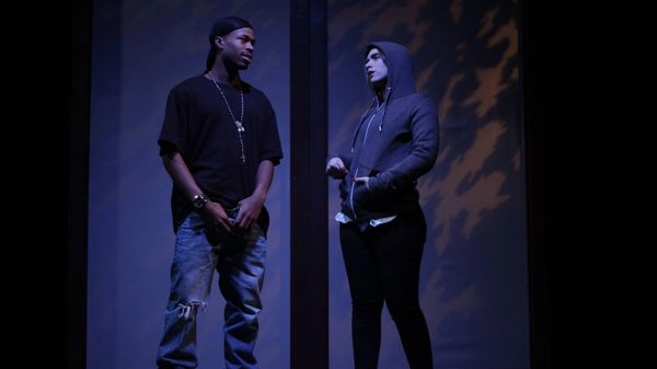 Two people on a stage talk to each other.