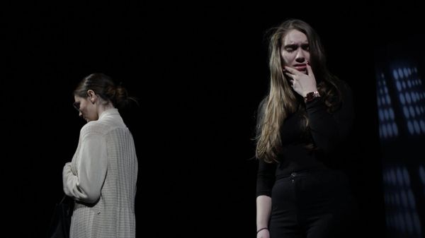 Two white people turn away from each other on a stage.