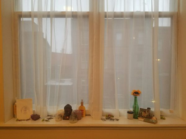 A curated cluttered windowsill with flower petals candles, polaroid photos, etc.