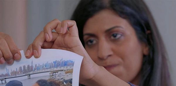 Woman with an unhappy face tears a photo of herself kissing another woman.