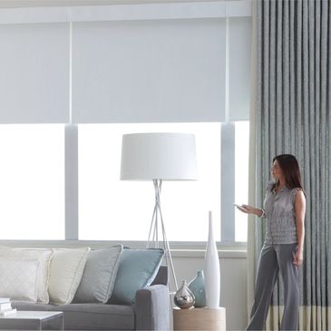 lady using remote to open and close shades in large high window