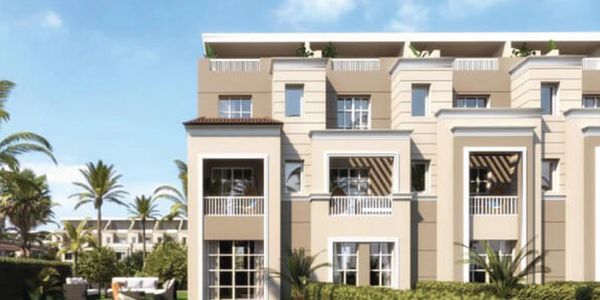 Modern beige apartment building with balconies and green garden area.