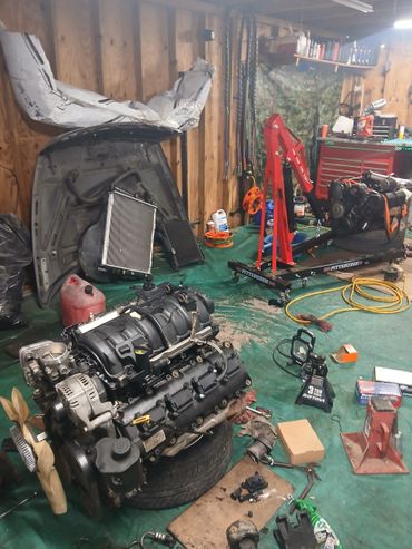 Car engines and tools in a wooden garage workspace.