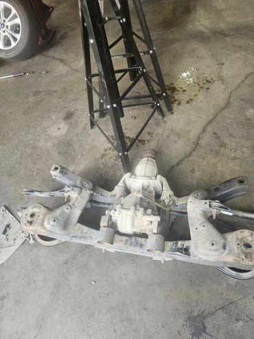 Car rear axle assembly with differential on garage floor.