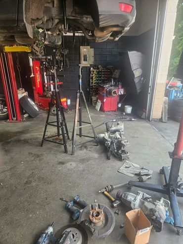 Car lifted on stands with parts and tools scattered in a garage.